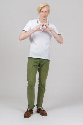 Front view of a young man showing a heart sign with fingers