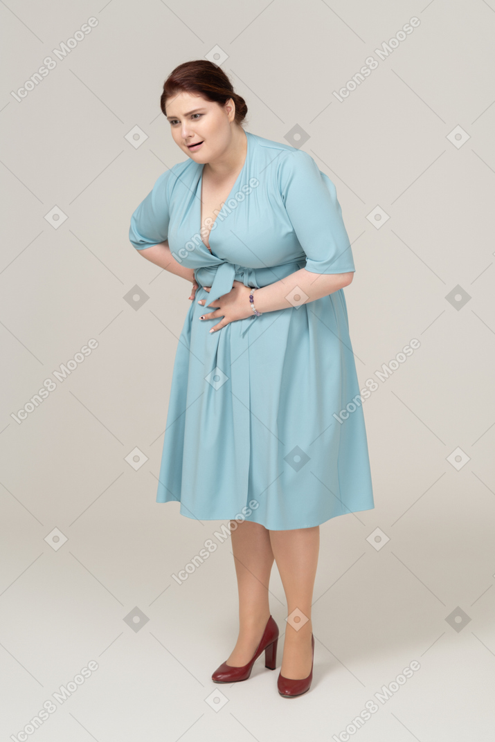 Вид спереди женщины в синем платье, страдающей от боли в животе