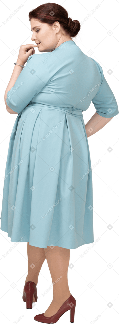 一个穿蓝色裙子的女人咬着手指的后视图