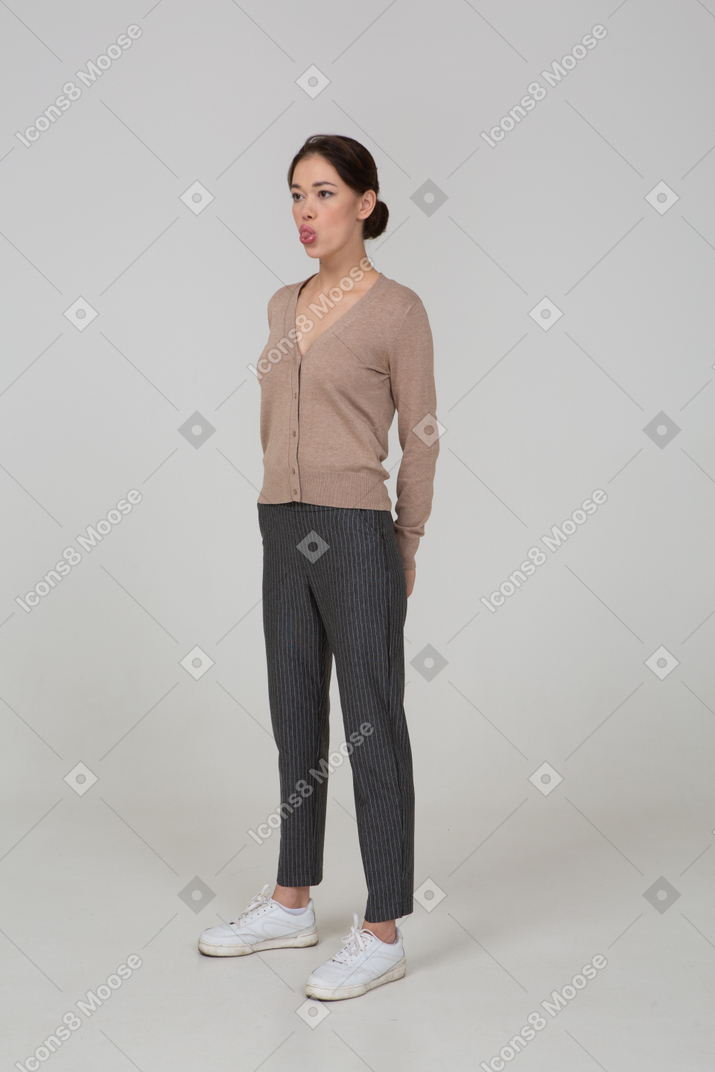 Three-quarter view of a young lady in pullover and pants showing tongue