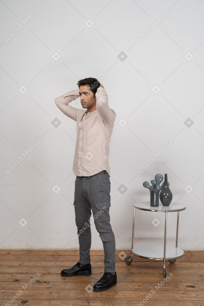 一个穿着休闲服的男人双手放在脑后摆姿势的侧视图