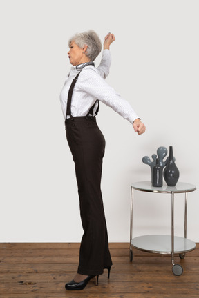 Вид сбоку пожилой женщины в офисной одежде, протягивающей руки