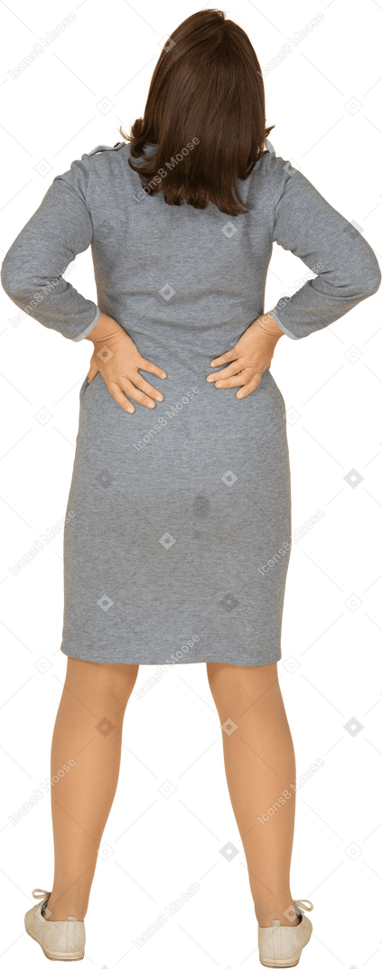 Rear view of a woman in grey dress suffering from pain in lower back