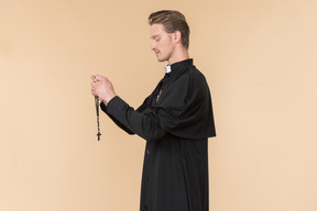 Catholic priest praying using prayer beads