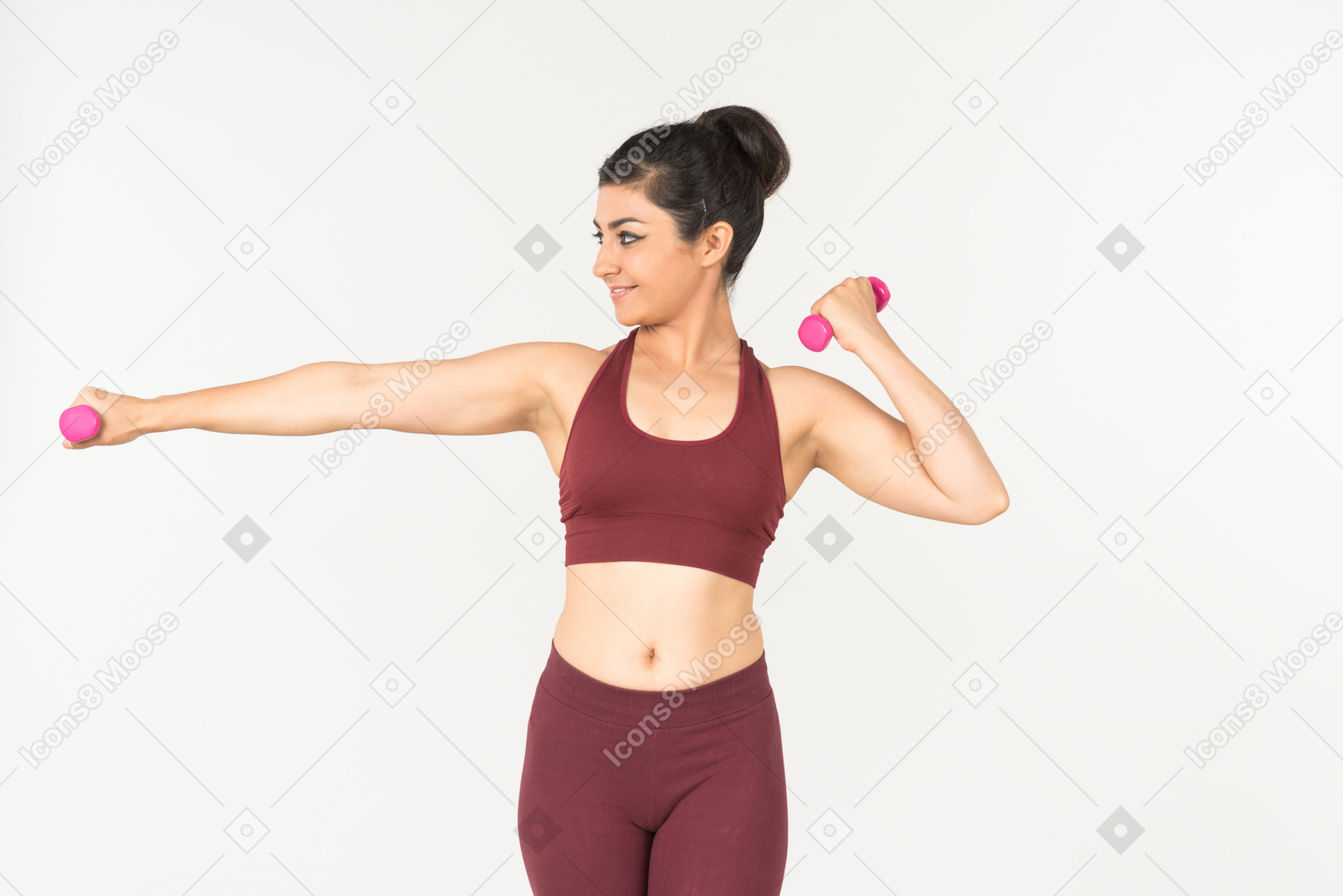 Young indian woman in sportswear holding hand weights and looking aside