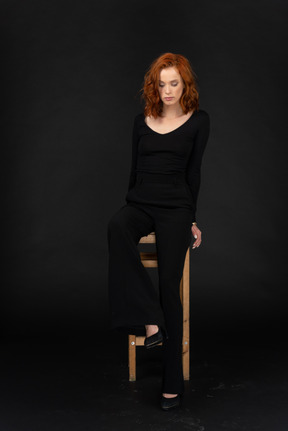 A frontal view of the beautiful woman sitting on the high wooden chair with closed eyes