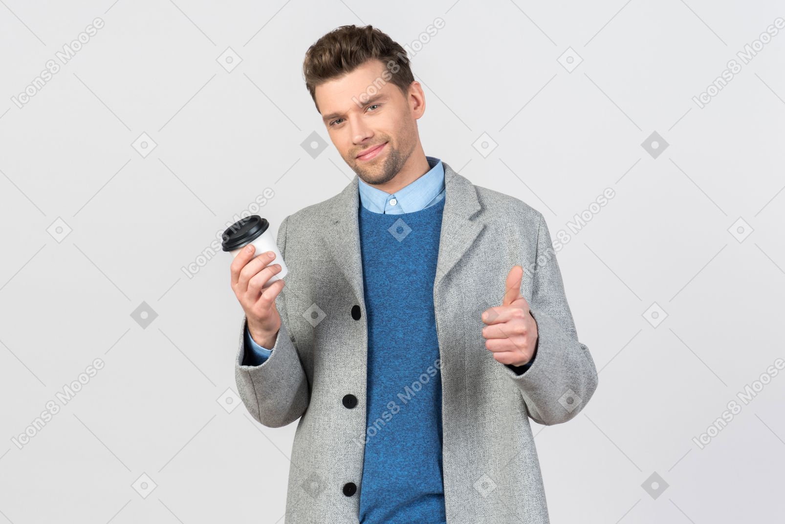 Apuesto joven sosteniendo café y mostrando el pulgar hacia arriba