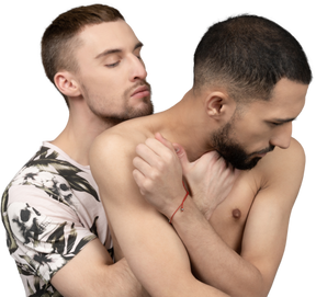 Close-up of a young man back hugging and trying to kiss his shirtless lover