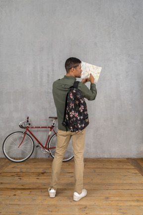 Back view of a man with a backpack and a map asking for directions