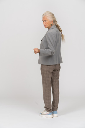 Rear view of an old lady in suit showing fist