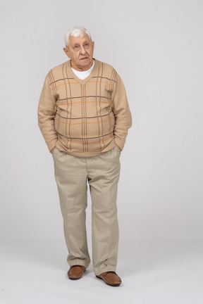 Vista frontal de um velho em roupas casuais em pé com as mãos nos bolsos