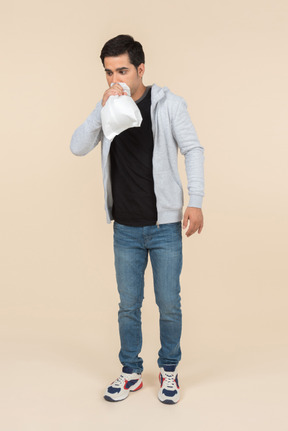 Young caucasian man breathing into a paper bag