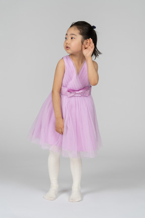 Little girl in pink dress trying to hear something