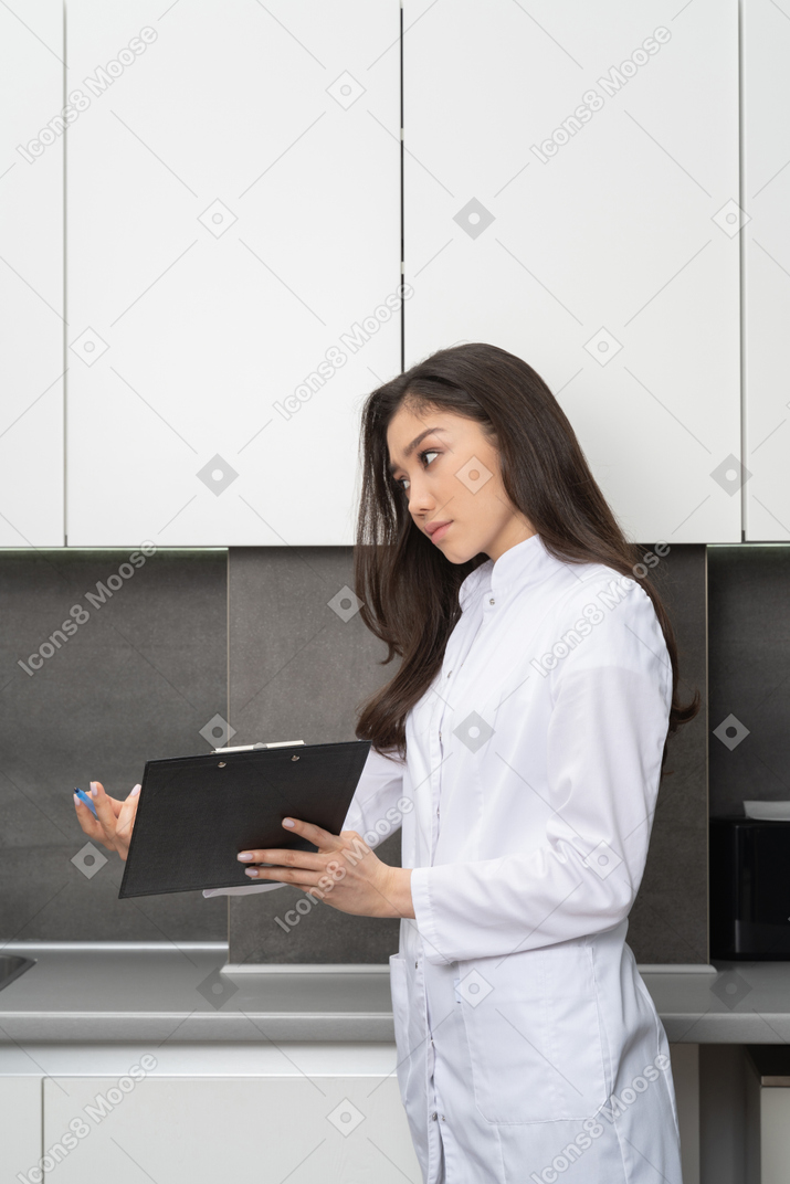 Vista de três quartos de uma jovem médica pedindo para assinar os papéis