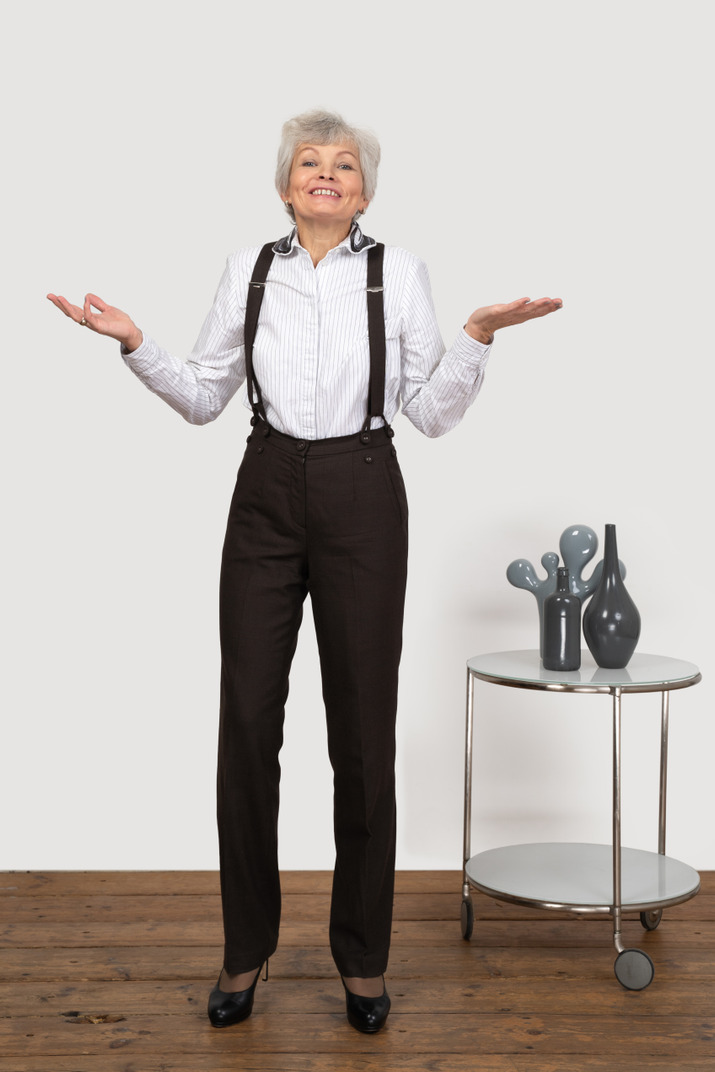 Front view of a smiling old lady in office clothing raising her hands