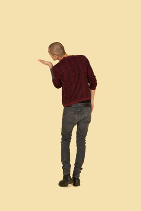 Back view of a young man in red pullover sending an air kiss