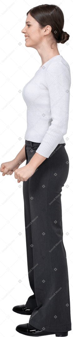 Side view of a delighted young woman in office clothing clenching fists