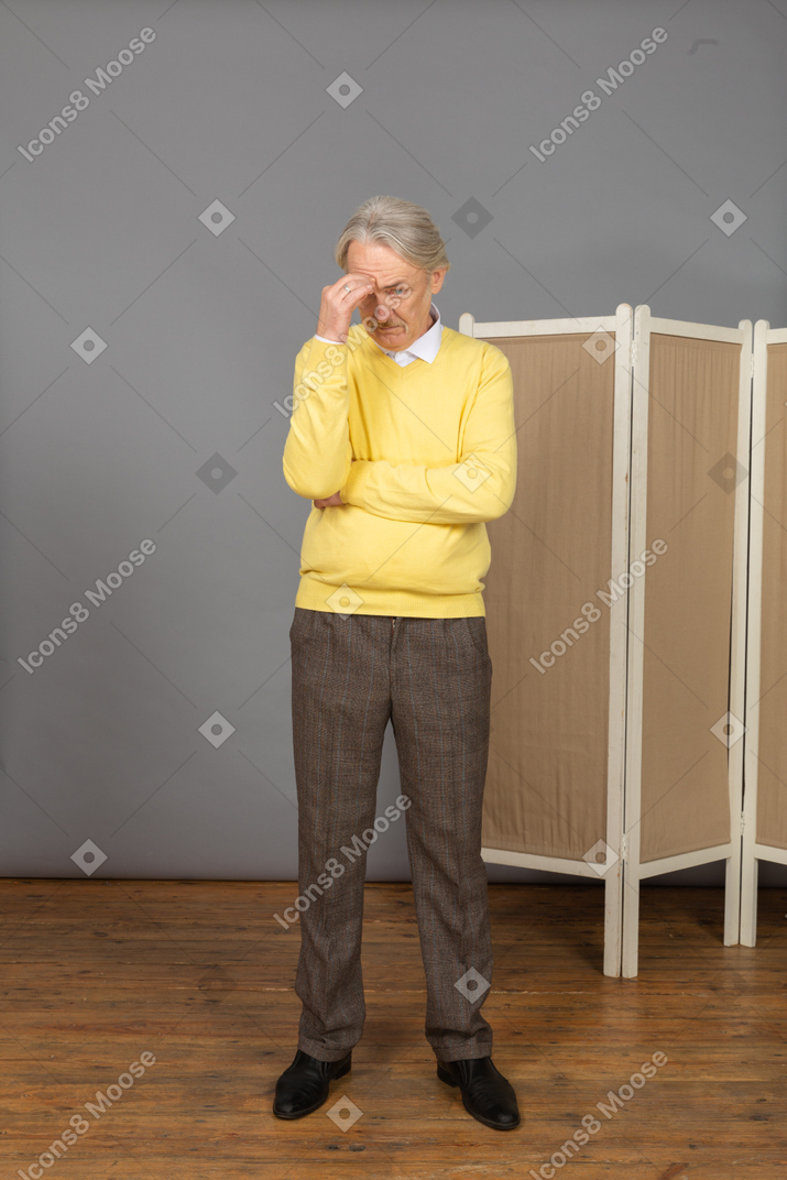 Front view of a withdrawn old man touching his head
