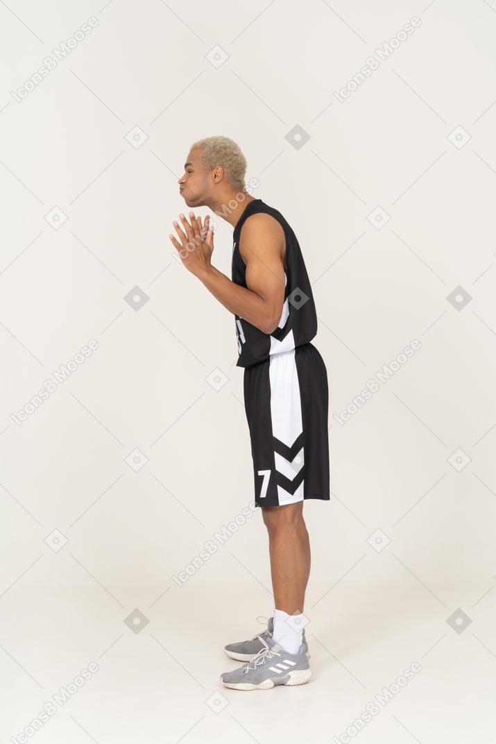 Side view of a young male basketball player blowing cheeks & raising hands