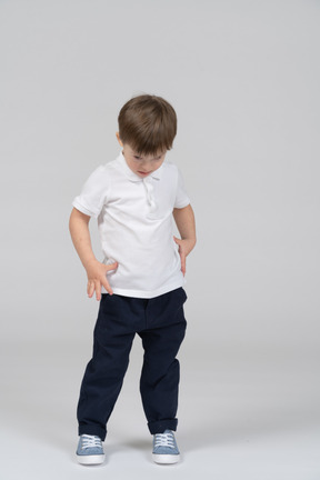 Front view of little kid standing and looking down