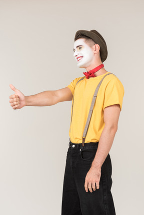 Happy male clown standing half sideways and showing thumb up