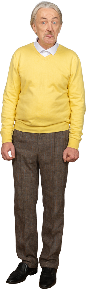 Front view of an old man in a yellow pullover showing tongue