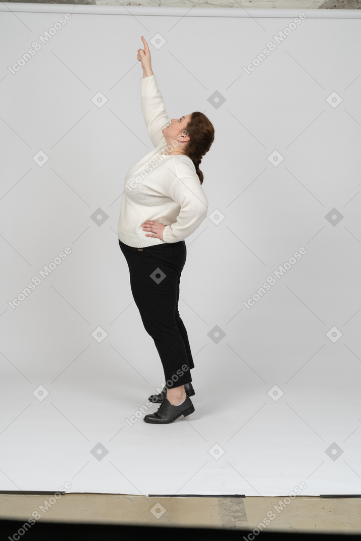 Side view of a plump woman in casual clothes standing with raised arm