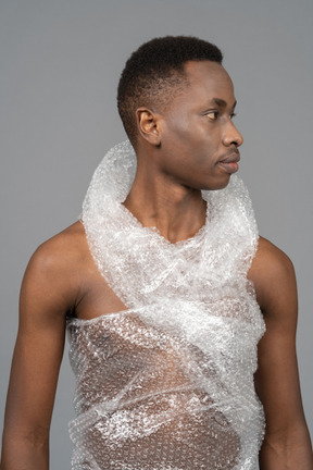 Ein porträt eines nackten afrikanischen jungen mannes, eingewickelt in plastik