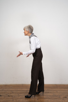 Side view of a smiling gesticulating old lady in office clothing