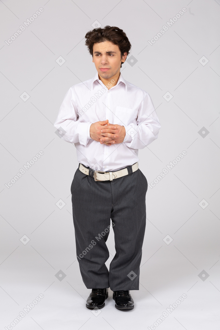 Uomo in abiti formali in piedi con le mani piegate sullo stomaco
