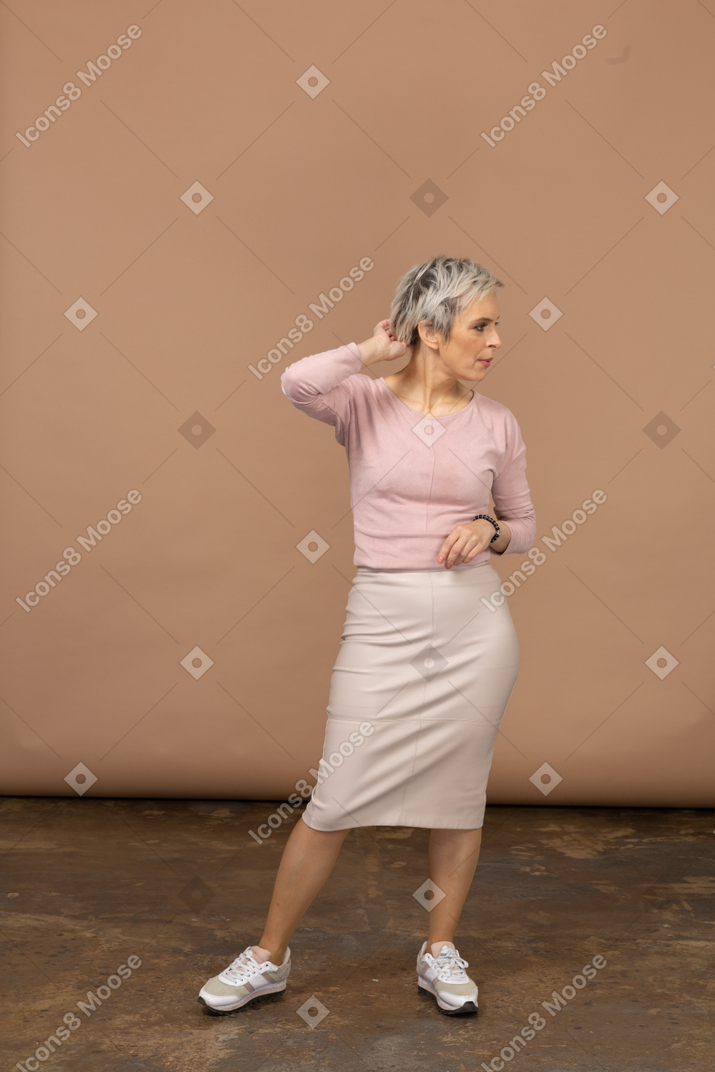 Vista frontal de uma mulher com roupas casuais, posando com a mão atrás da cabeça
