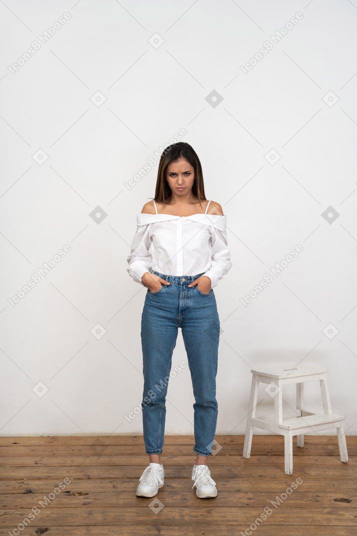 Grumpy woman standing with hands in pockets