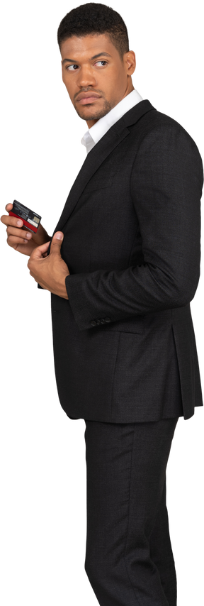 Side view of a young man in black suit holding bank card