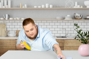 A man in a blue shirt is cleaning a table