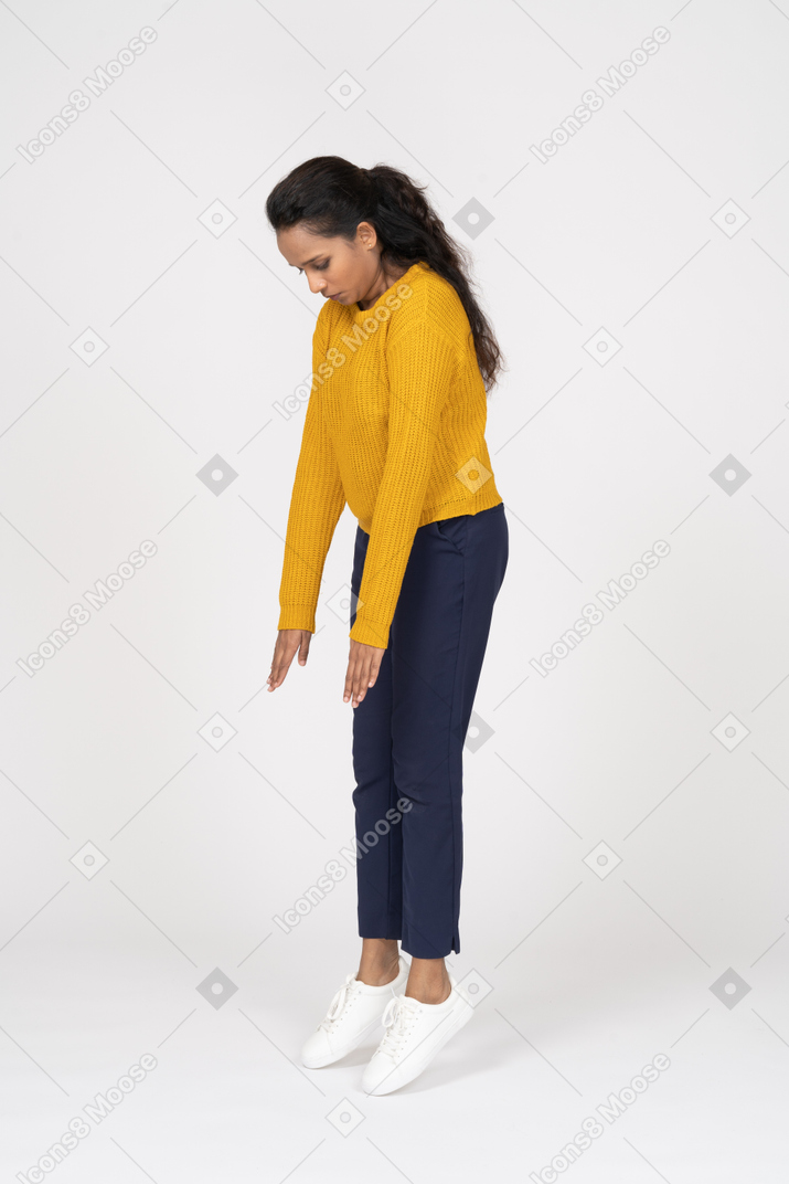 Side view of a girl in casual clothes standing on toes and looking down