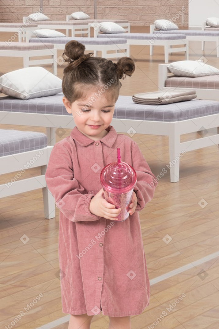 A little girl holding a drink in a room