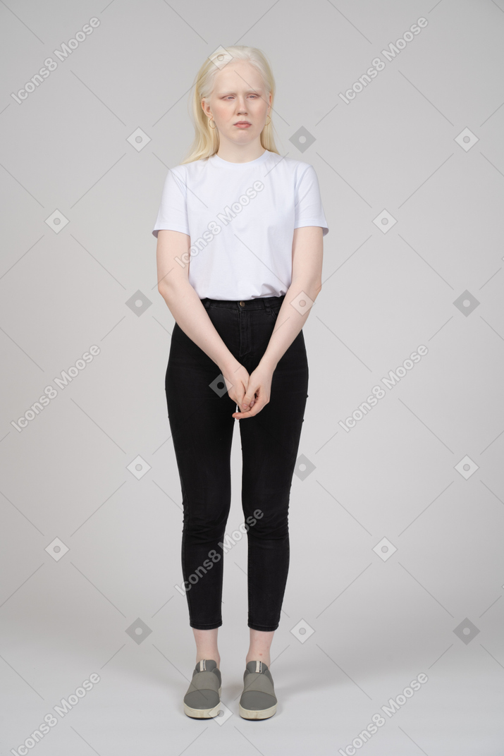 Femme bouleversée dans des vêtements décontractés debout avec les mains jointes