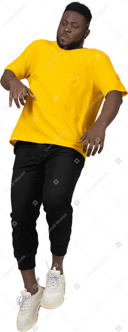Vista frontal de um jovem de pele escura em uma camiseta amarela pulando para trás