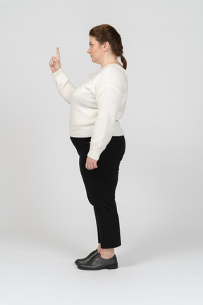 Mujer de talla grande en ropa casual apuntando hacia arriba con un dedo