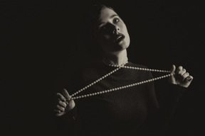 Woman tightening a string of beads on her neck