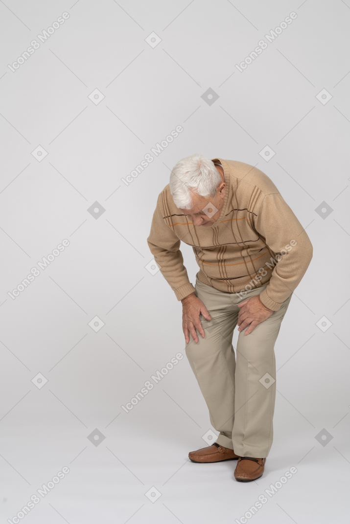 Vista frontale di un vecchio in abiti casual chinarsi
