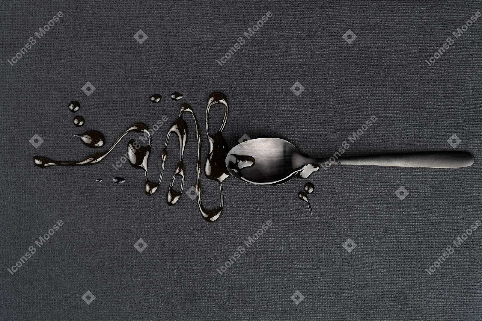 Metal tea spoon with liquid on the black
