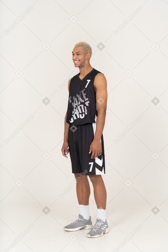 Vista de três quartos de um jovem jogador de basquete sorridente, parado