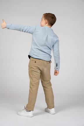 Вид сзади на мальчика, показывающего большой палец вверх