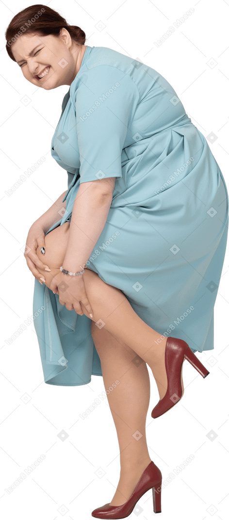 Side view of a woman in blue dress touching her injured knee