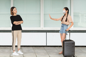 Woman with suitcase stopping another woman