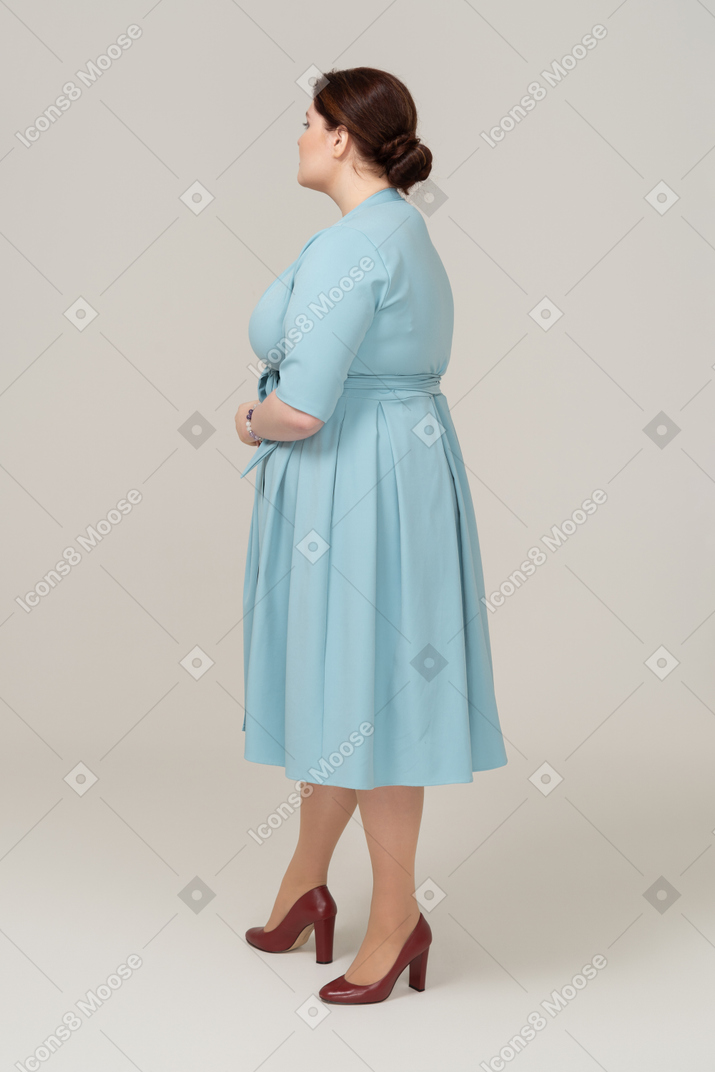 Mulher de vestido azul em pé de perfil