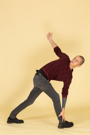 Full-length of a young man in a red pullover stretching his back