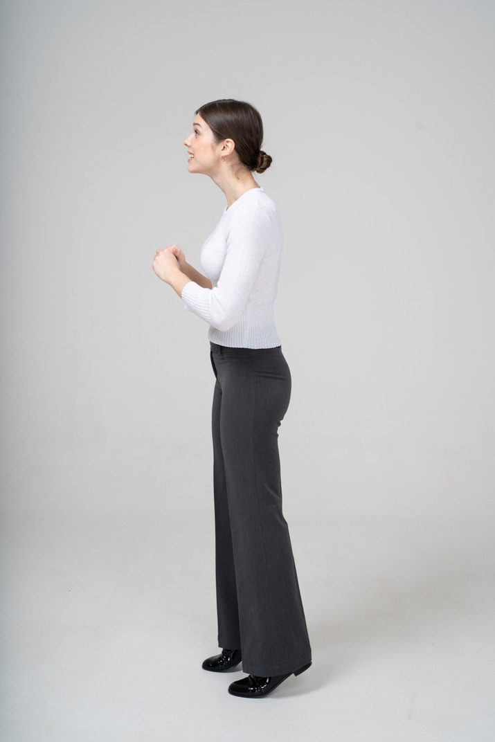 Side view of a woman in black pants and white blouse