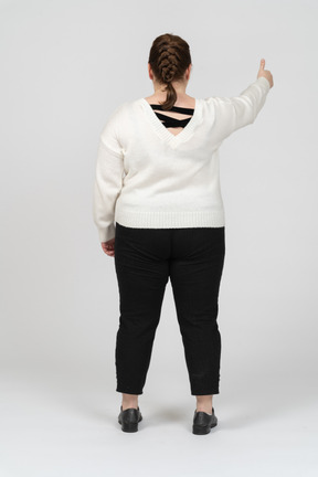 Mujer de talla grande en suéter blanco mostrando el pulgar hacia arriba